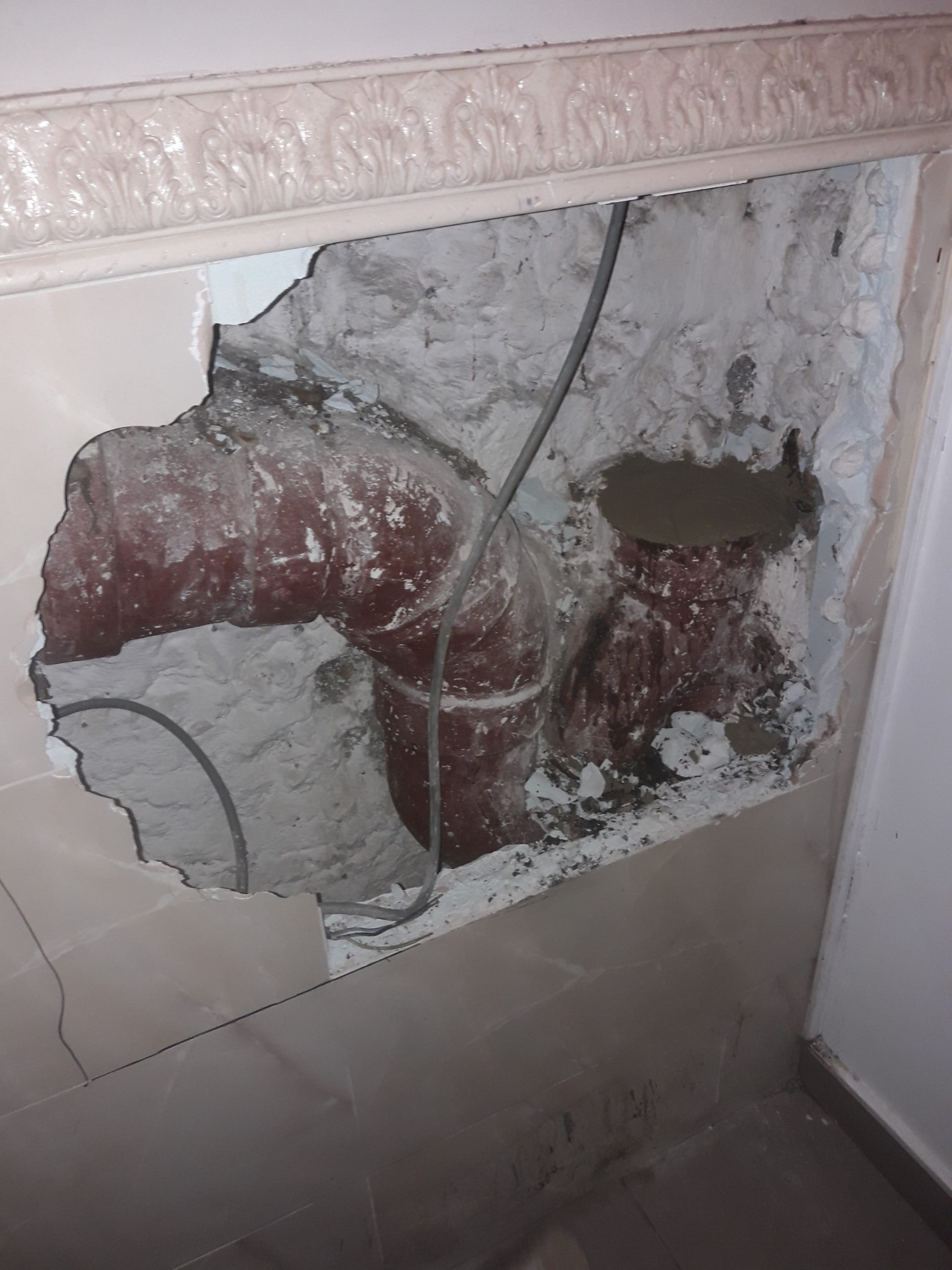 Siphon engorgé dissimulé derrière un mur